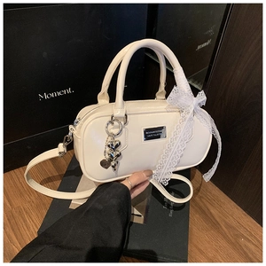 Detail of cream bowling bag featuring silver heart pendant and lace bow decoration