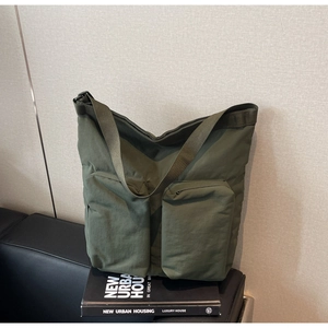 Detail of army green nylon tote bag with dual zipper pockets and adjustable strap