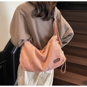 Detail of pink corduroy crossbody bag with drawstring design and leather logo patch