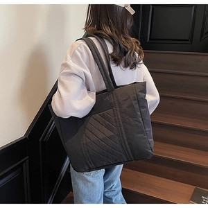 Action shot of large black quilted tote bag with diamond pattern for daily commuting