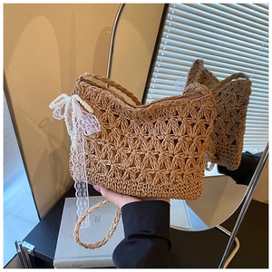 Detail einer Strohtasche mit hohlem Blumenmuster und Anhänger aus Spitze und Perlen