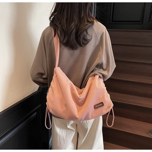 Detail of pink corduroy shoulder bag showing fabric texture and leather logo patch