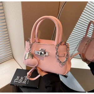 Detail of pink lychee leather handbag featuring silver hardware and heart charm