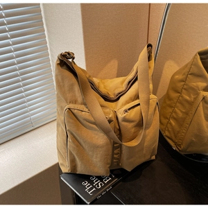 Close-up of khaki tote bag featuring dual front zipper pockets and nylon texture detail
