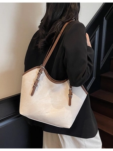 Chic cream tote bag with brown straps worn by a model in a modern urban setting