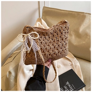 Detail einer handgewebten Strohtasche mit 3D-Blumenstruktur, Perle und Spitzenanhänger