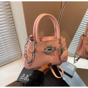 Detail of pink lychee leather bucket bag with silver lock and heart charm