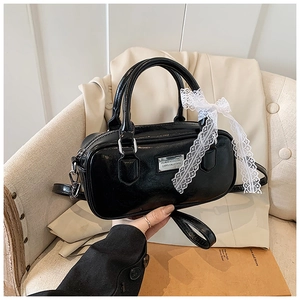 Detail of black bowling bag featuring silver hardware and a white lace bow accent