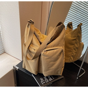 Detail of khaki nylon tote bag showing large zipper pockets and adjustable wide strap