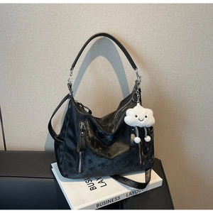 Détail d'un grand sac fourre-tout noir texturé avec poches zippées et breloque