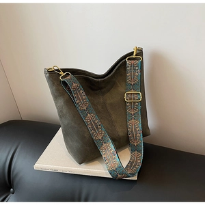 Close-up of wide bohemian embroidered strap and olive green tote with gold hardware