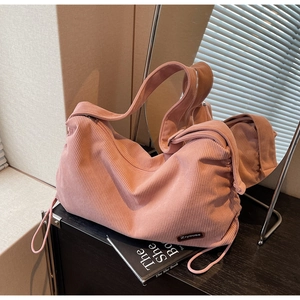 Detail shot of pink corduroy shoulder bag showing soft ribbed texture and leather logo tag