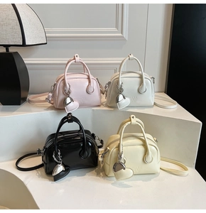 Detailed shot of four leather bowling bags in pink white black and yellow with charms
