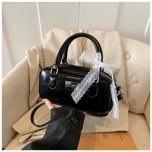 Close-up of black glossy bowling bag with white lace bow and silver logo plate