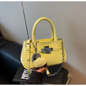 Detail view of bright yellow bucket bag with lychee texture leather and heart pendant
