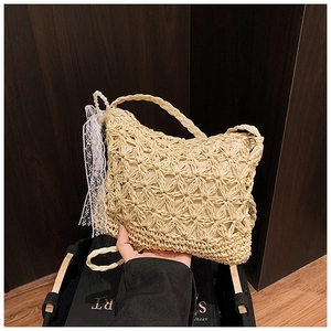 Detail des hohlen Stern-Häkelmusters auf beige Strohtasche mit Perlenspitzenanhänger