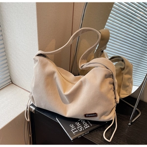 Detailed texture of off-white corduroy tote bag with small brown leather logo patch