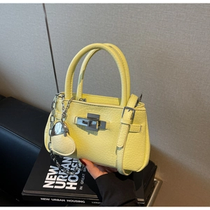 Detail of yellow lychee texture leather handbag with heart charm and silver chain strap
