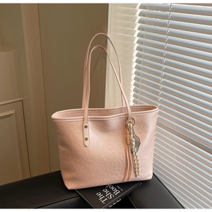 Close-up of pink large tote bag with textured leather and decorative rope pendant