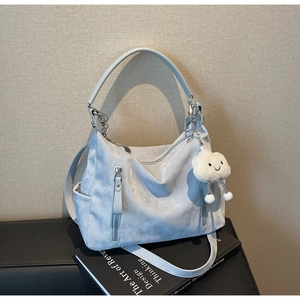 Détail macro du sac fourre-tout en nylon bleu clair avec fermetures éclair argentées et charme