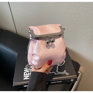 Detail shot of a pink satin mini bag with silver clasp and elegant chain strap texture