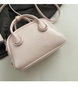 Detail of light pink Boston bag with embossed lettering and soft leather texture