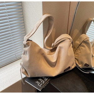 Detailed macro view of beige corduroy hobo bag with drawstring and leather logo tag