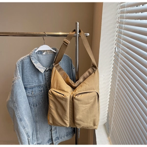 Detail of khaki utility tote bag featuring double front zippers and wide adjustable strap