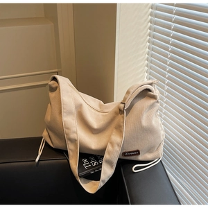 Close-up of beige corduroy shoulder bag showing vertical texture and brand leather logo