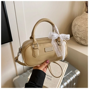 Detail of beige bowling handbag with lace bow and metal plaque shown in a lifestyle setting