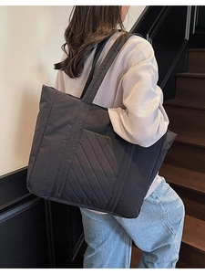 Large black quilted canvas tote bag with padded shoulder straps for daily commuting use