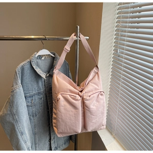 Detail view of pink nylon crossbody bag with dual front zippers on a metal rack