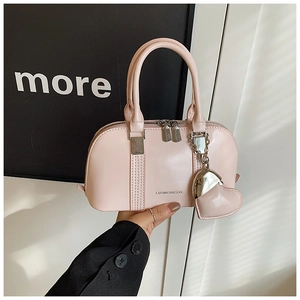 Detail of pink shell handbag with silver hardware and heart pendant on smooth leather