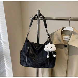 Détail du sac fourre-tout noir avec bandoulière chaîne et porte-clés nuage sur cintre