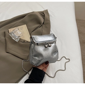 Close-up of mini silver bucket bag with pleated texture, vintage kiss-lock, and chain strap
