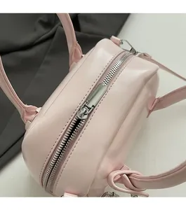 Close-up of smooth silver metal zipper and dual handles on pink faux leather pillow bag