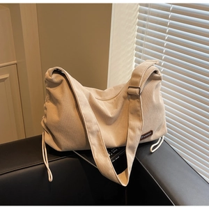 Detail of off-white corduroy tote bag showing textured stripes and brown leather logo tag