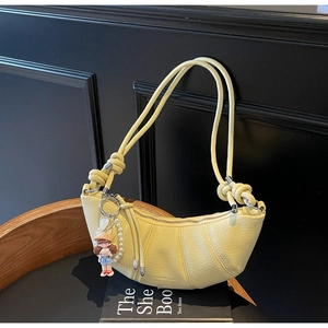 Détail du sac croissant jaune clair avec texture lychee et design plissé tendance