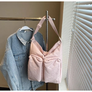 Close-up of large pink nylon tote bag with two front pockets and adjustable strap