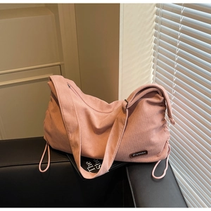 Detail of pink corduroy tote bag featuring side drawstrings and brand label decoration