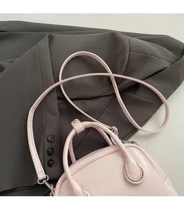 Pink leather crossbody bag detail placed on a grey blazer for a modern aesthetic
