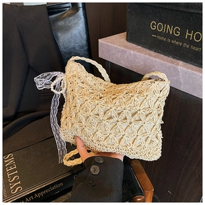 Detailansicht der beigefarbenen Strohtasche mit Spitzenbesatz und Perlenanhängern