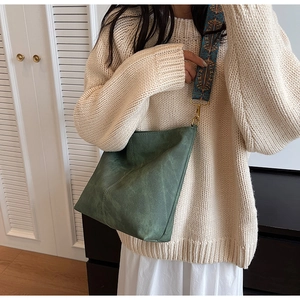 Détail du cabas vert foncé avec large bandoulière tissée colorée dans un décor minimaliste
