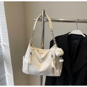 Détail du grand sac cabas crème avec poches zippées verticales et pendentif en peluche