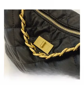 Détail du fermoir en métal doré et de la texture du cuir noir matelassé du sac