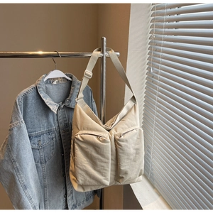 Detail of minimalist beige canvas tote bag with large front pockets and wide strap