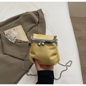 Detail view of yellow leather mini bucket bag with silver ball clasp and chain strap