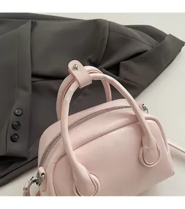 Close-up of the rounded light pink leather handles and silver hardware of the handbag