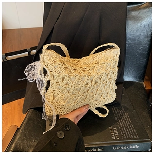 Nahaufnahme der beigen Strohtasche mit hohlem Blumenmuster und Perlen-Spitzen-Schleife