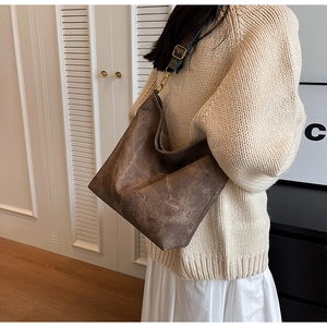 Detail of vintage brown tote bag featuring a textured finish and ethnic woven wide strap